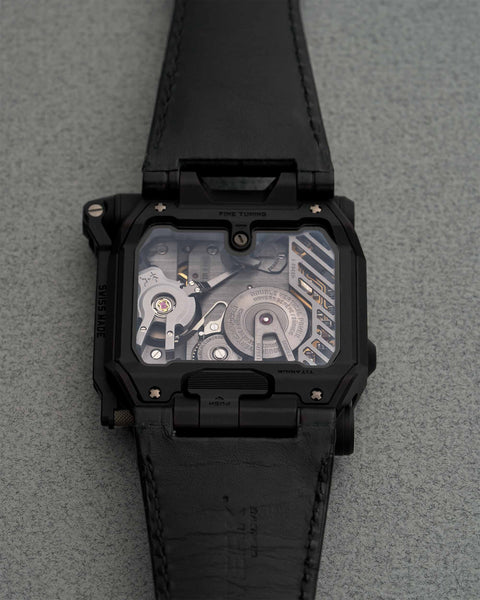 Back view of the URWERK EMC Black, displaying its intricate manual-winding movement, chronometric monitoring mechanism, and handcrafted Swiss engineering.